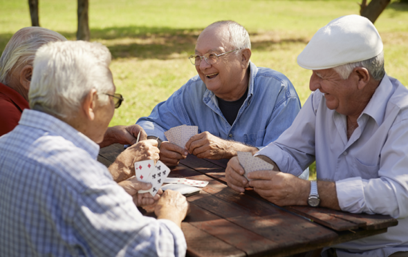 Four senior men playing a card game