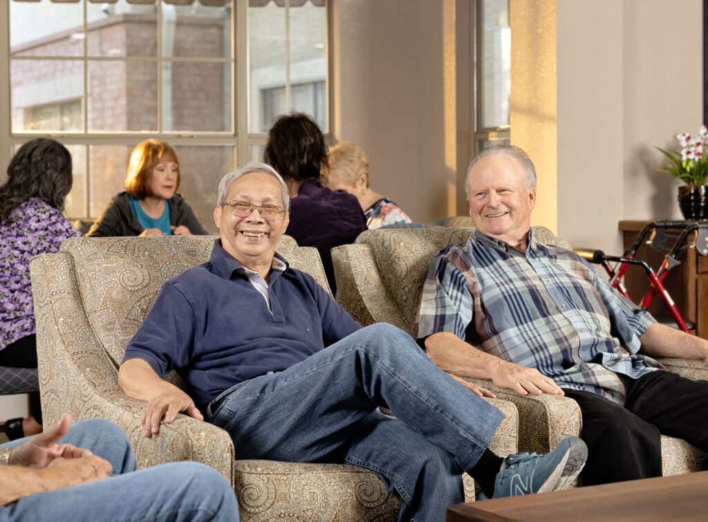 Seniors sitting together in a living room discussing the cost of senior living in a community