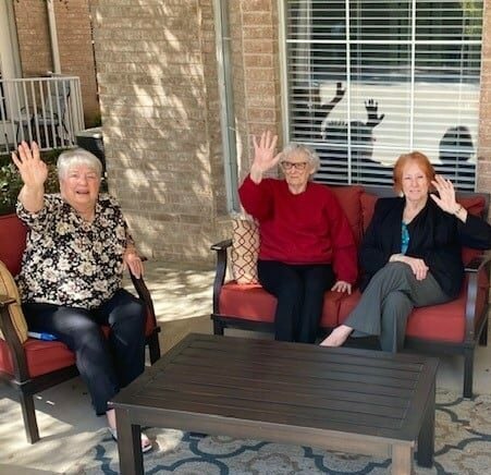 Senior women smile and wave at the camera at senior living community in North Richland Hills, Texas.