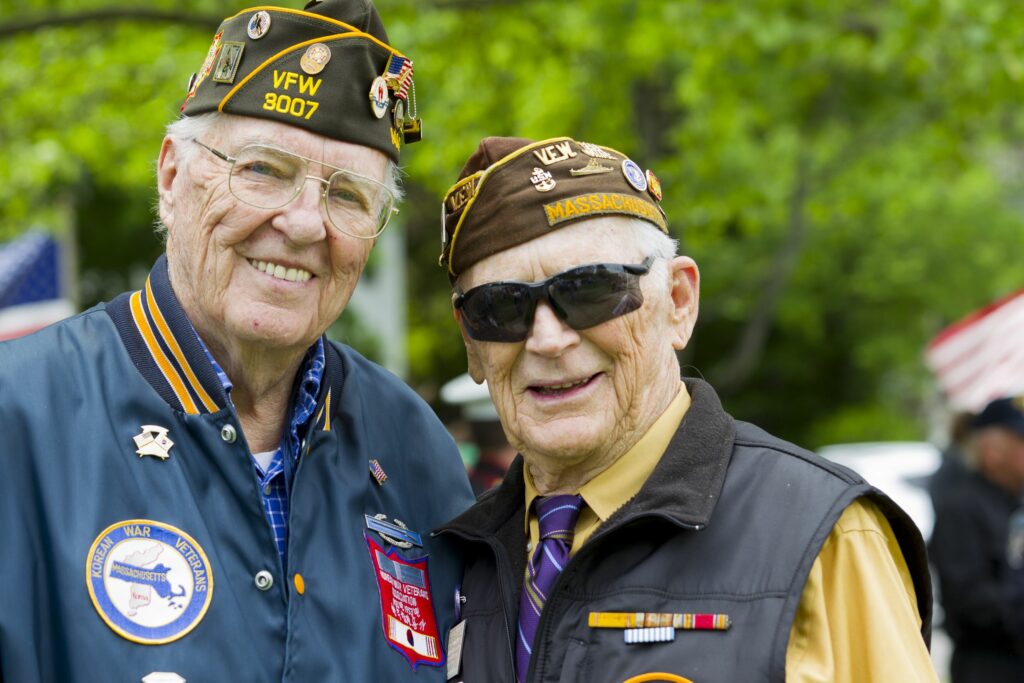 two senior men smile in their veteran attire