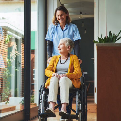 Woman being pushed through her assisted living community in a wheelchair