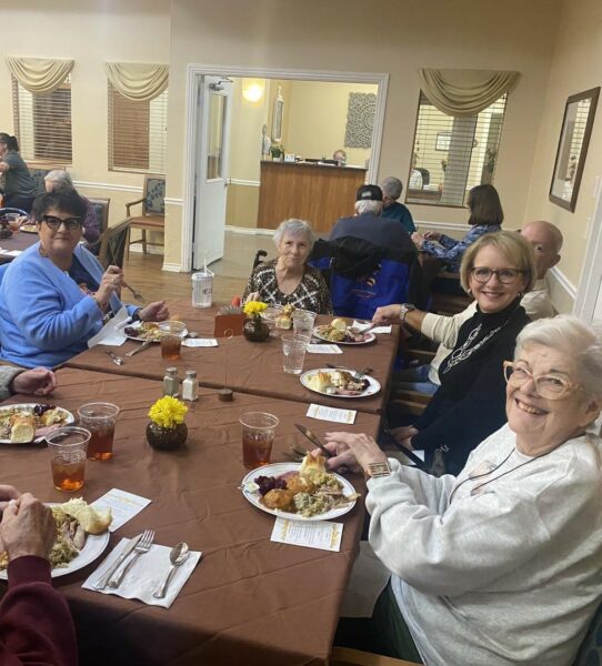 group of seniors and family members eat a Thanksgiving meal together
