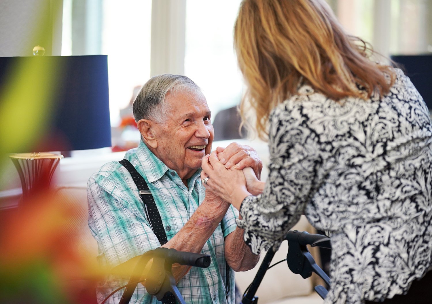 Senior man in Assisted Living holding hands with a female caregiver